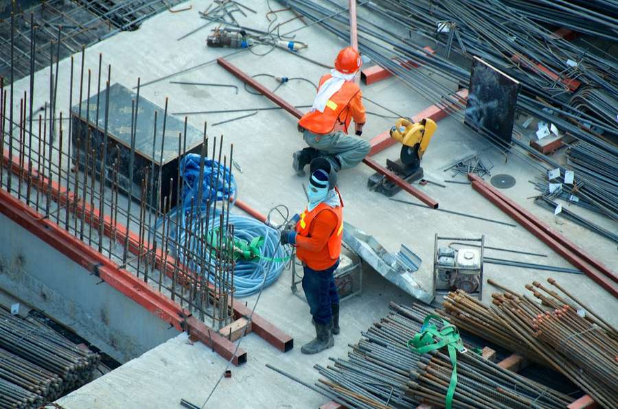 Construction workers in orange hi-vis working with steel reinforcement on site