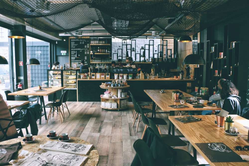 Busy independent cafe with a wooden counter, coffee bar and customers at tables